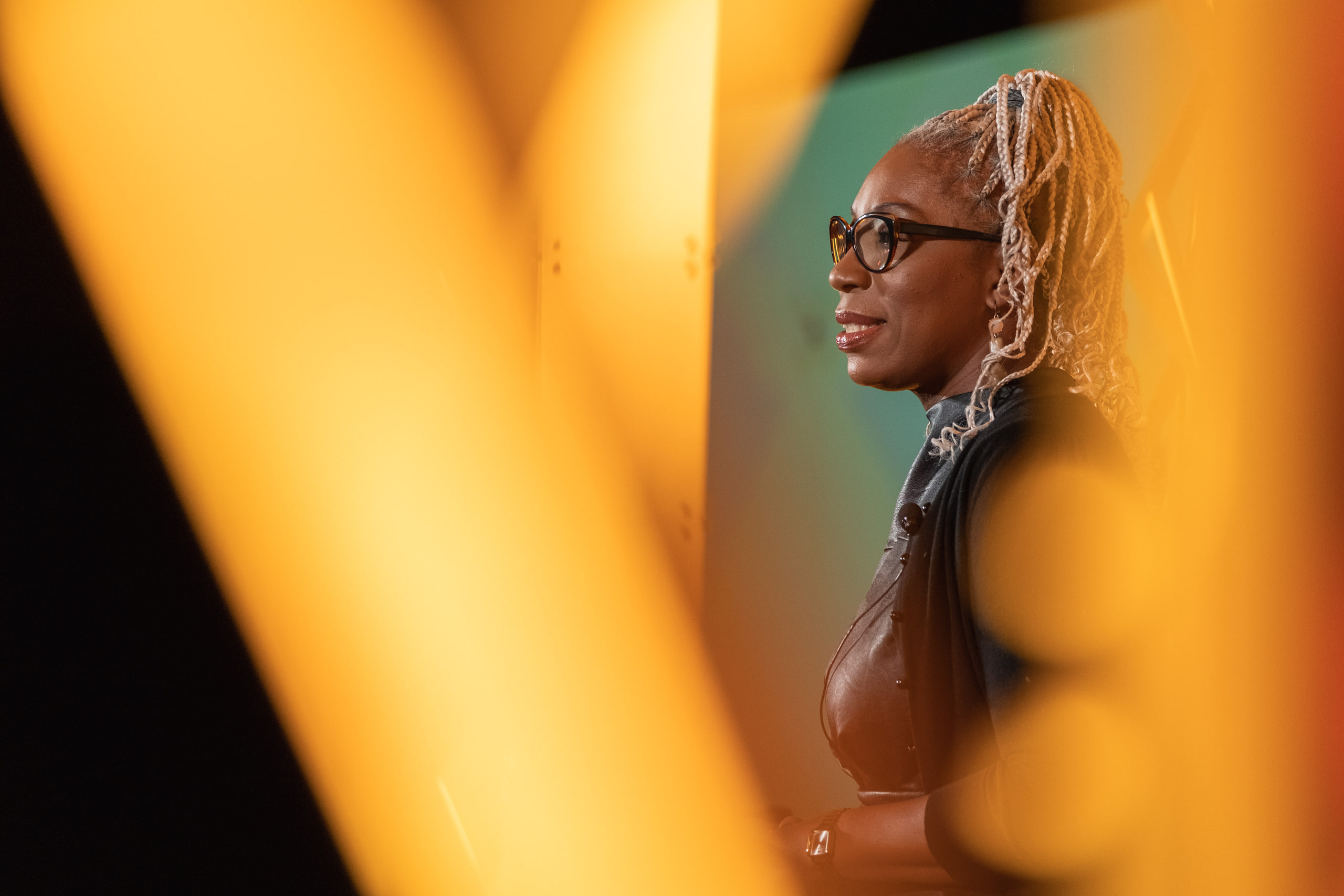 A conference attendee's face in gold stage light, photographed shallow