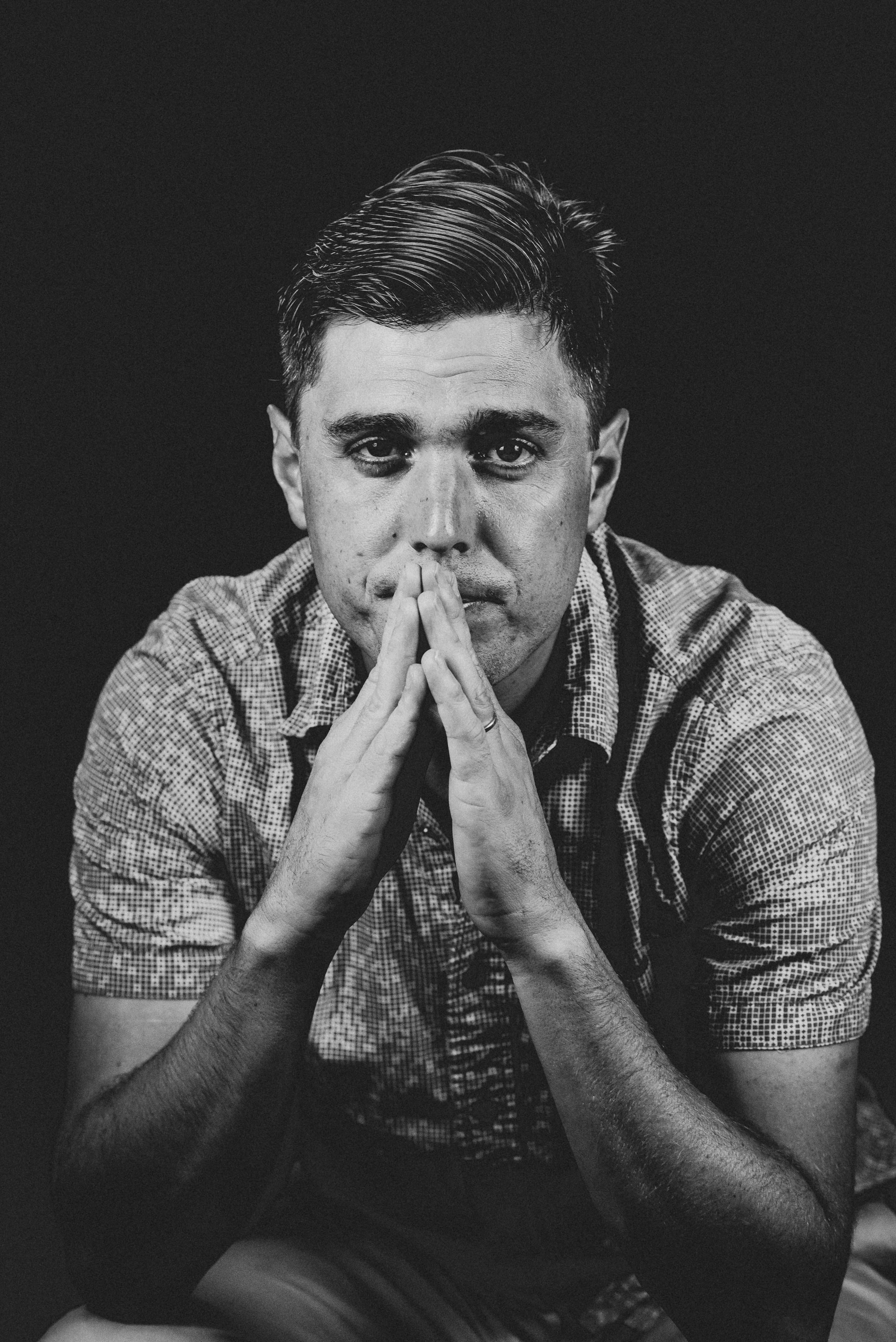 B&w hands clasped at the mouth, quiet.
