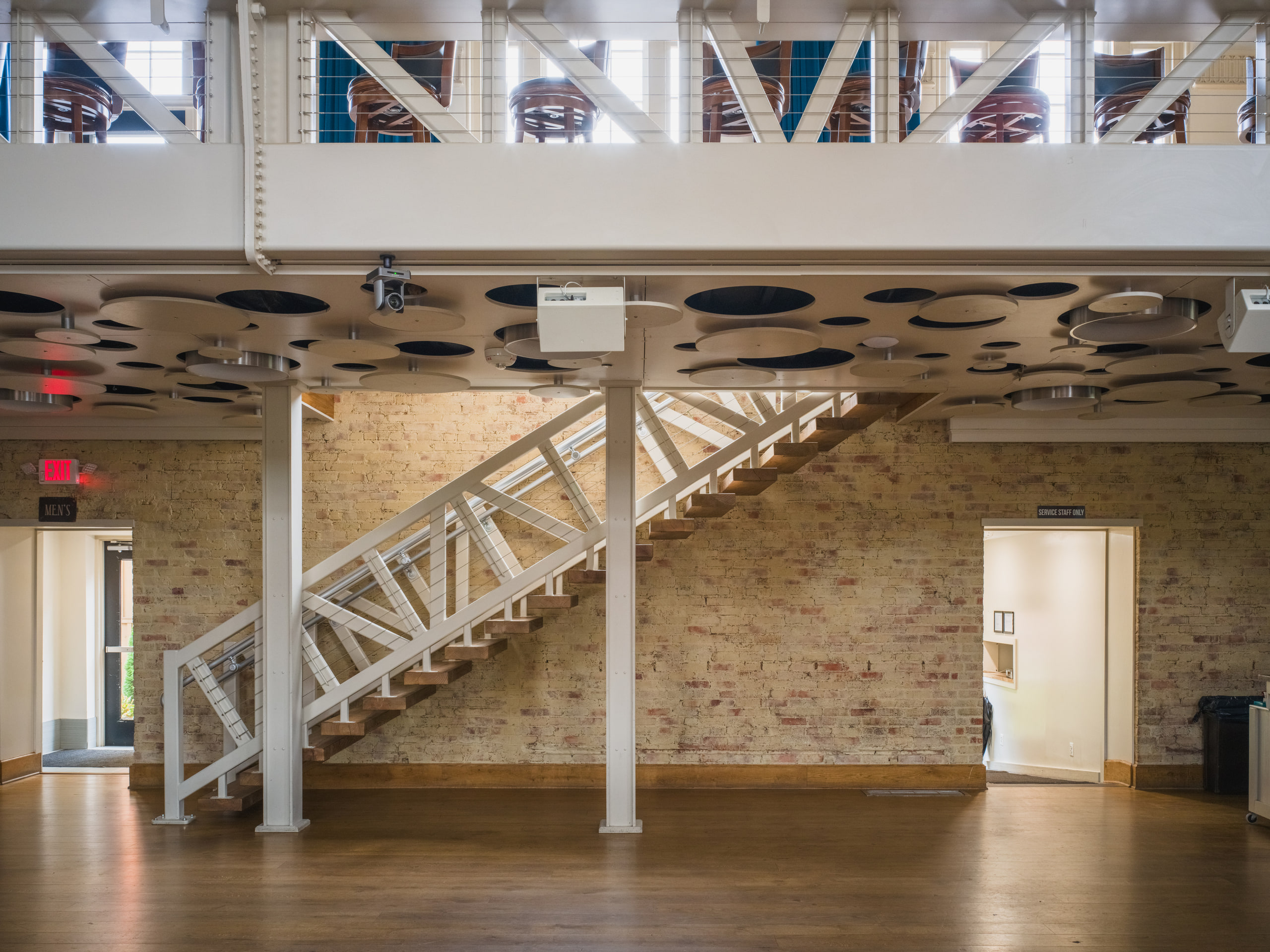 The bank hall, white mezzanine stair, perforated ceiling.
