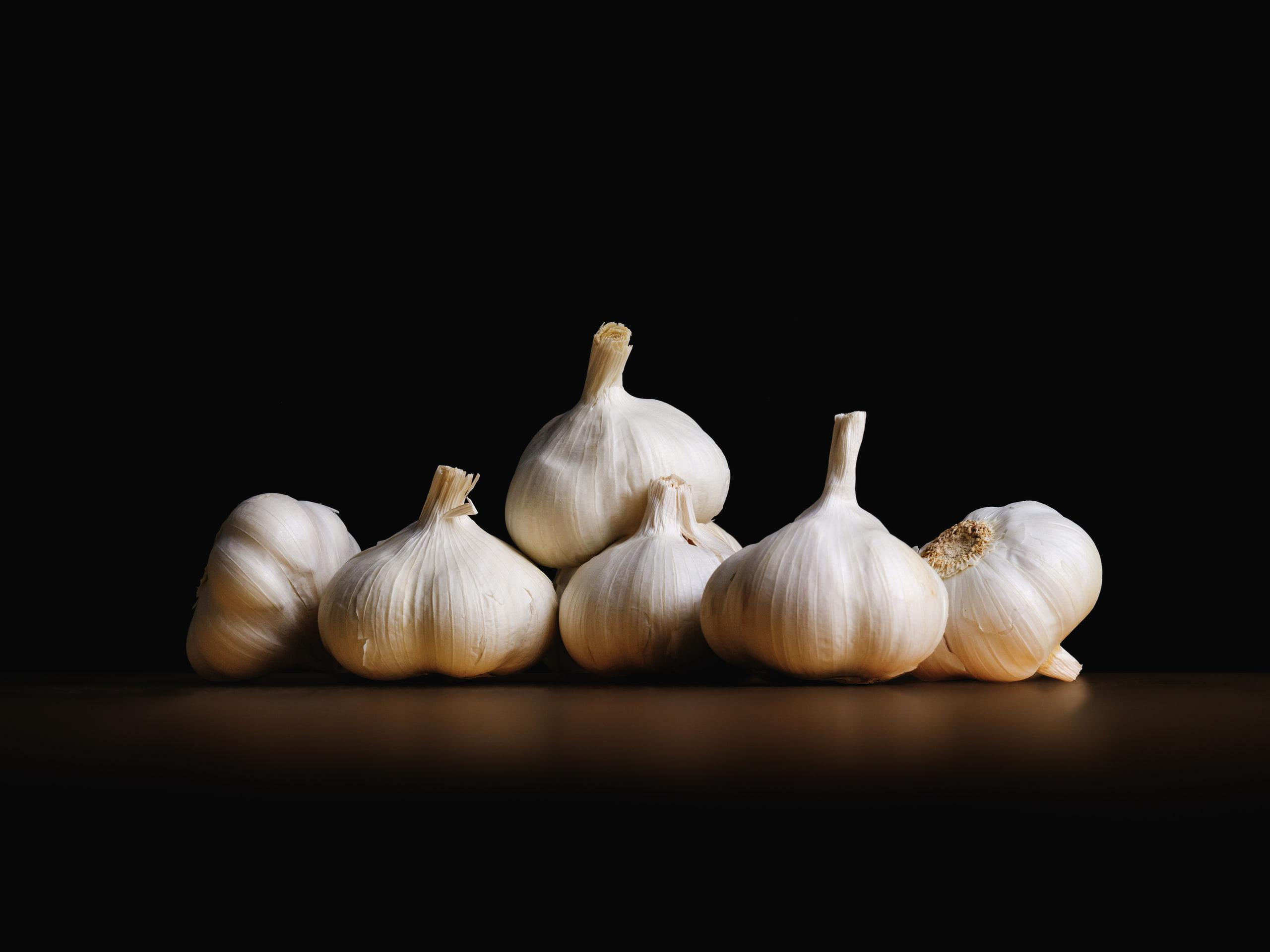 Garlic bulbs on black, hard light, single subject.