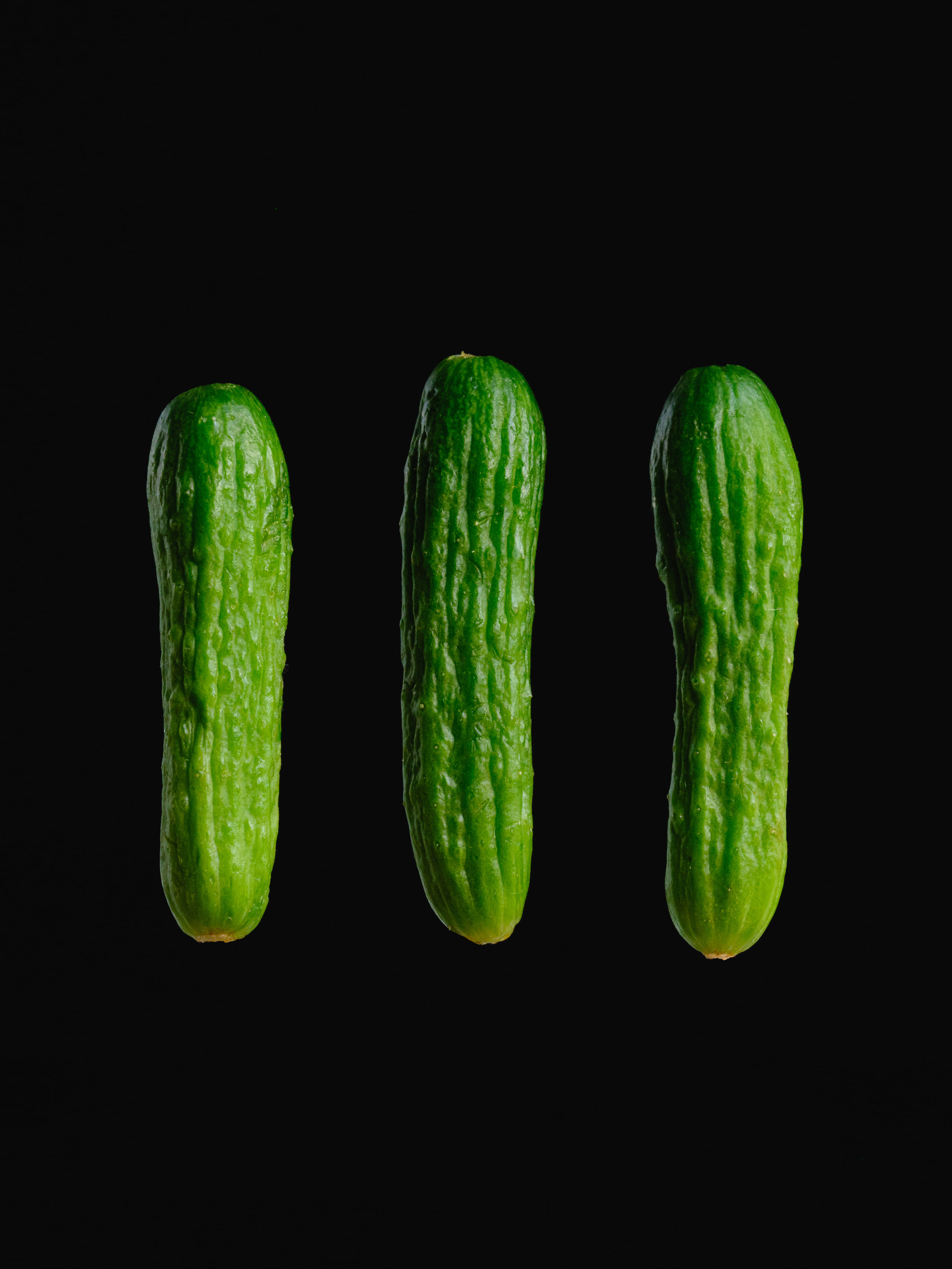 Three cucumbers on black, pure repetition with contrast.