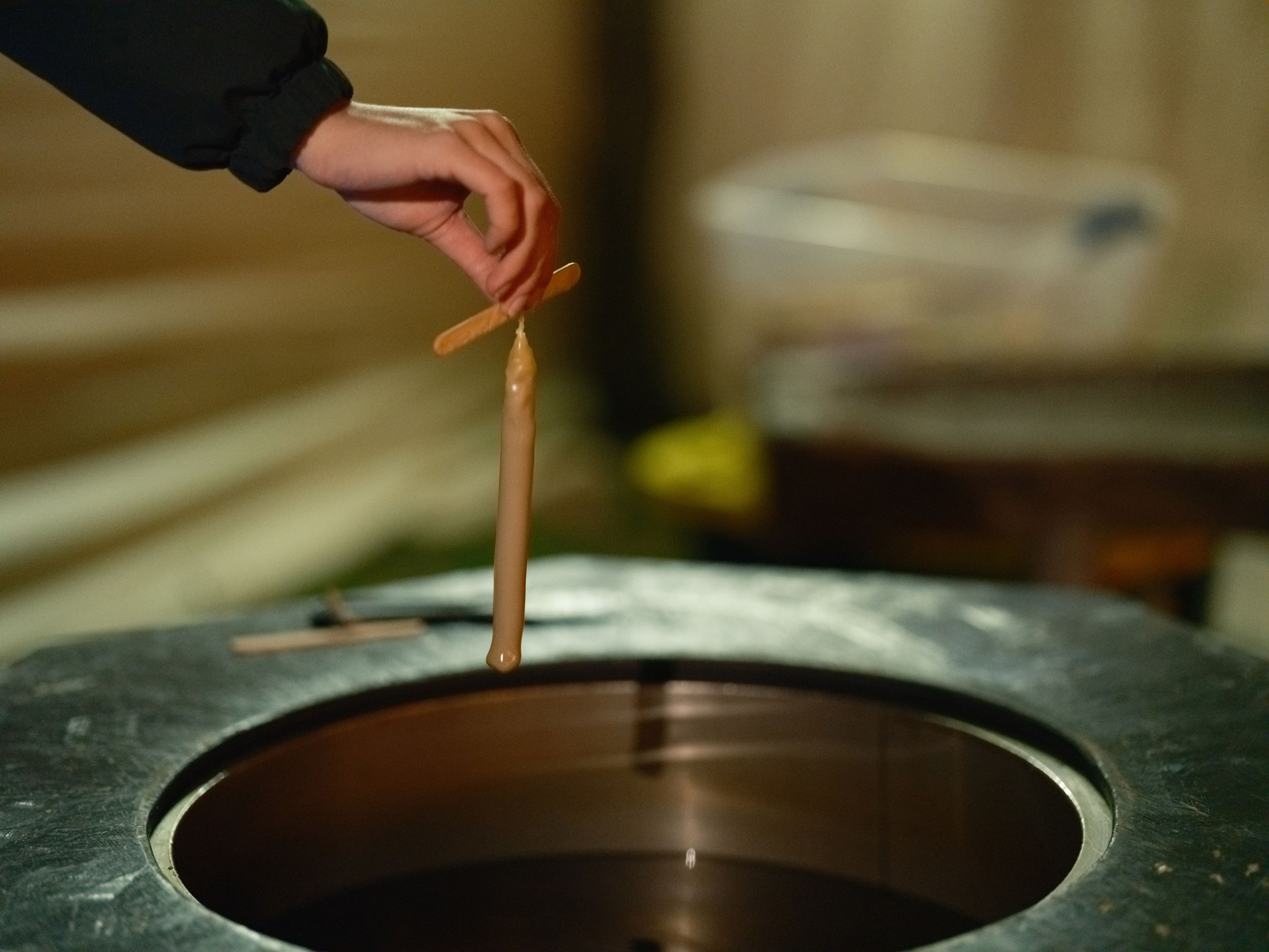 Hand stirring a copper pot, tactile and warm.