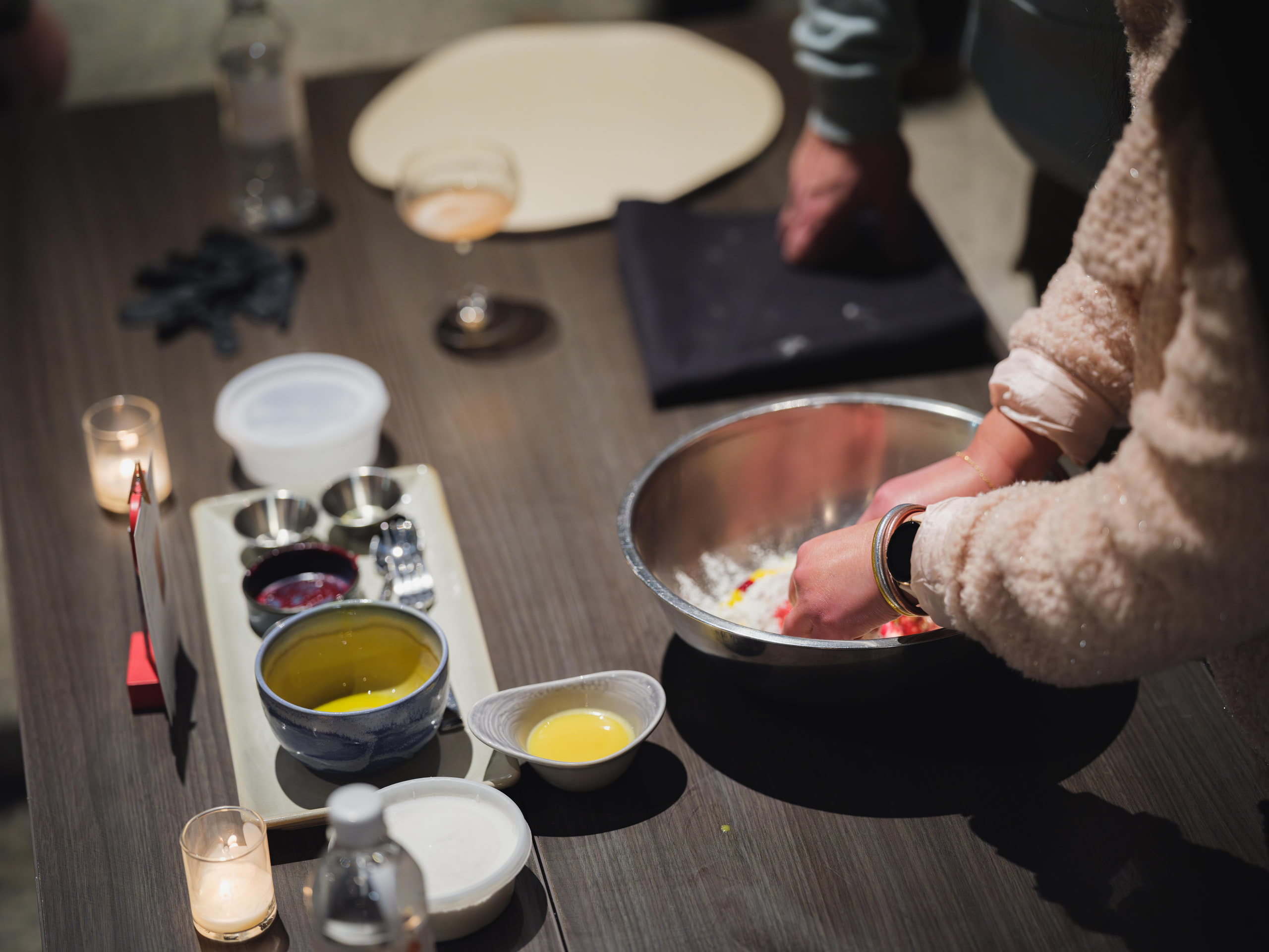 Hands plating with yellow sauce, dark ground.