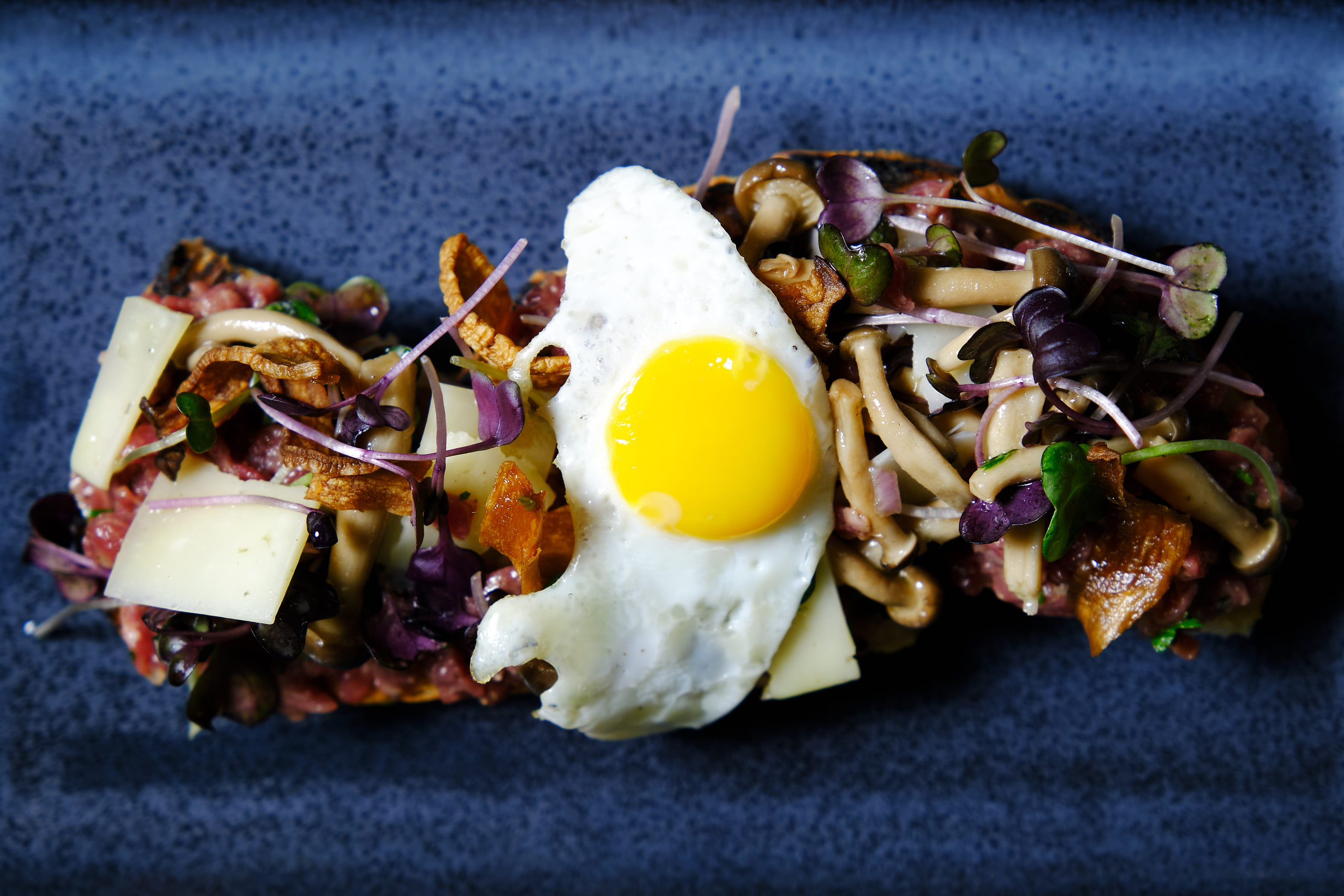 Egg and mushroom overhead on deep blue, color and edge.