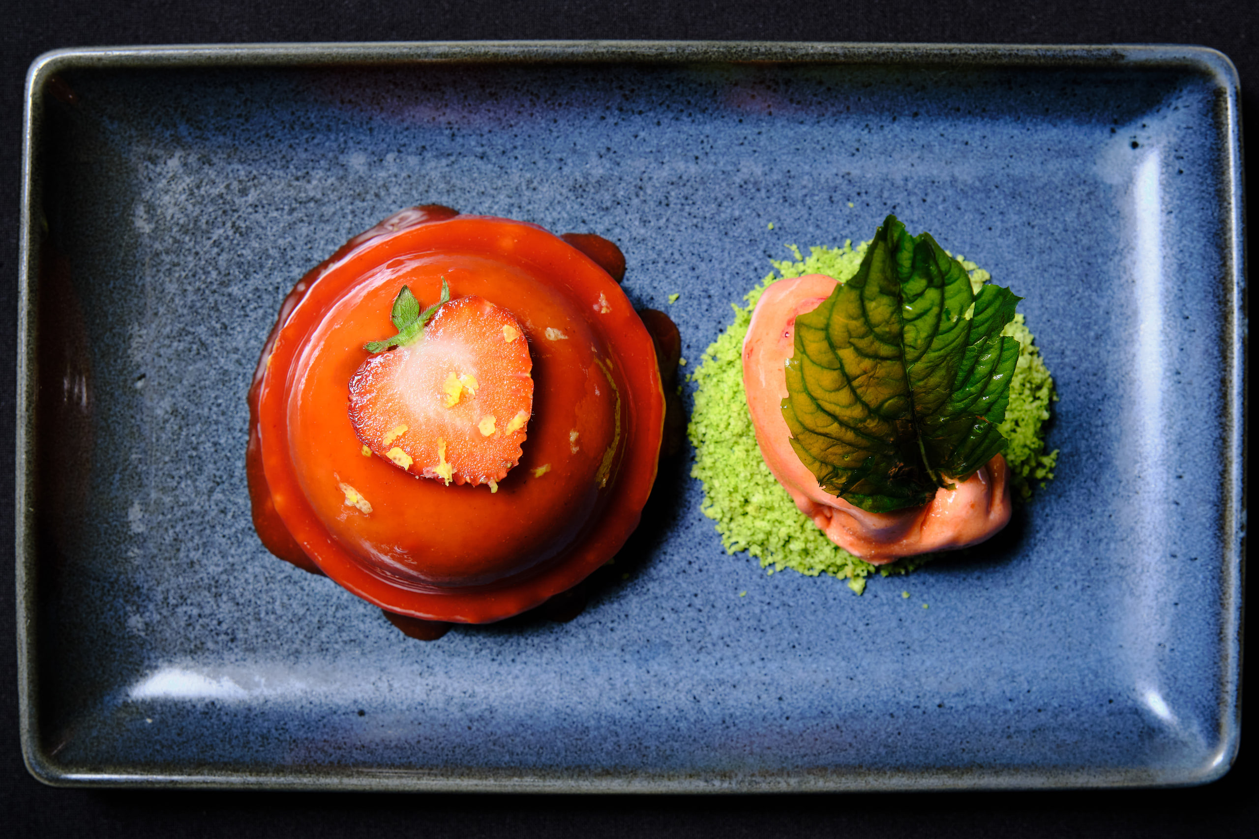Red glossy dome on a dark plate, one object.