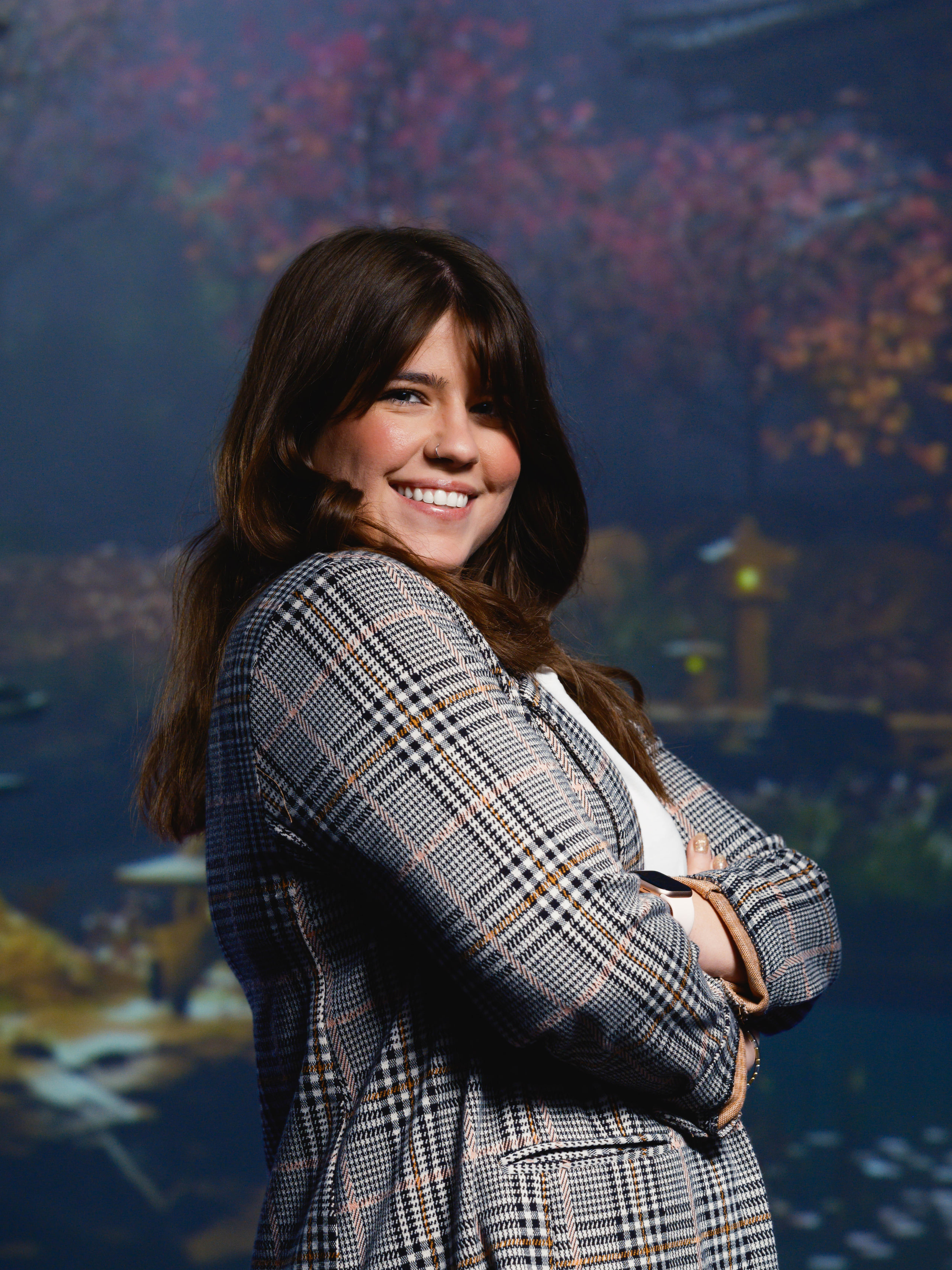 A corporate portrait made in a real session: a woman in a checked jacket against a painted backdrop, lit by the room