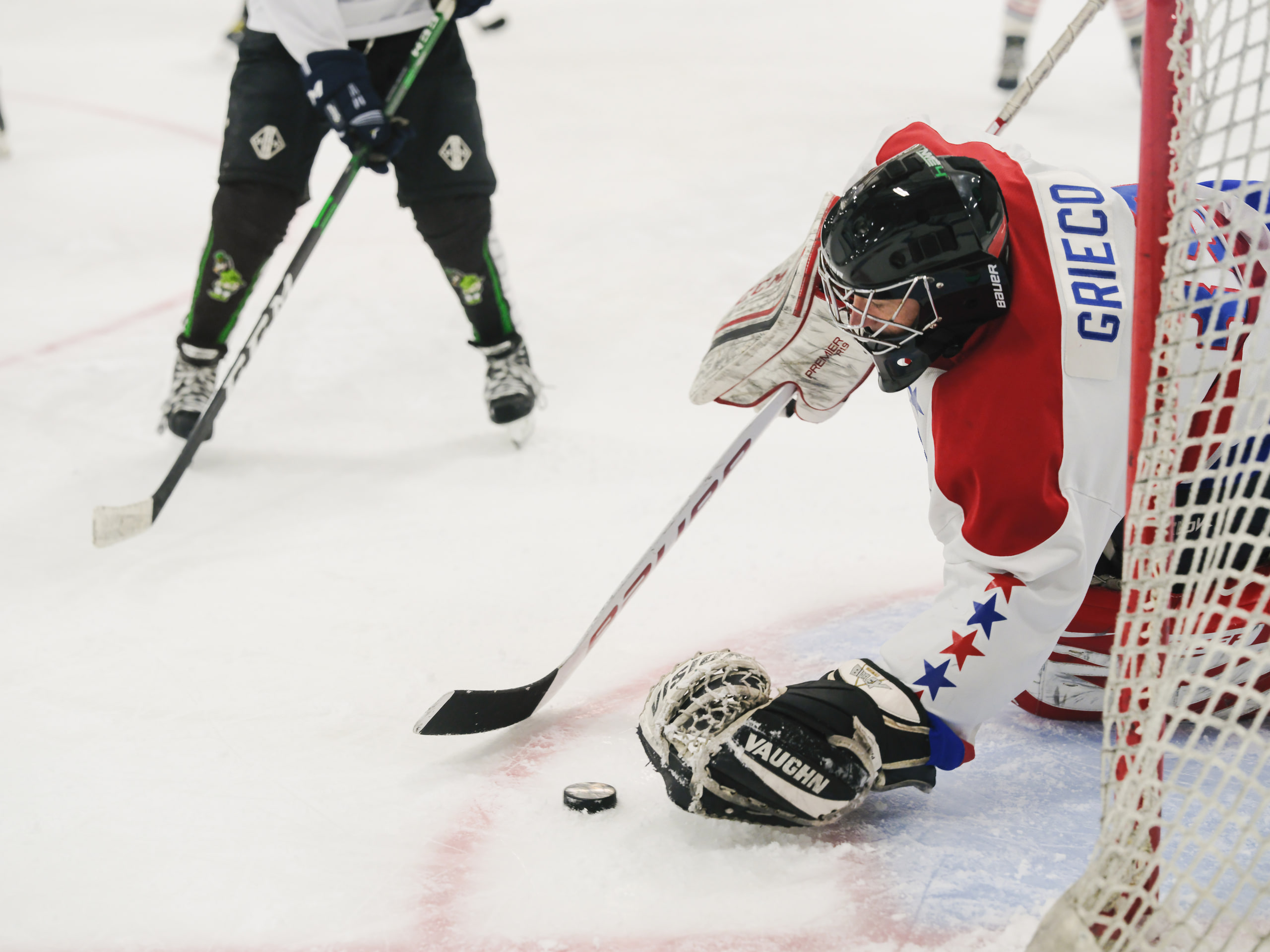 Goalie sprawled across the red crease, color and action.